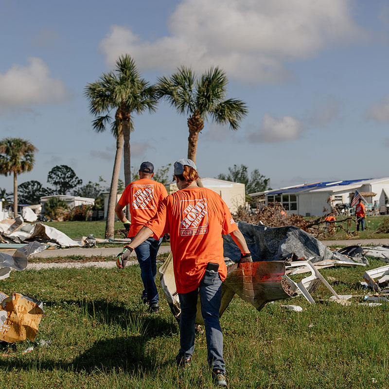 Team Depot volunteers carrying piece of a house through tornado destruction 