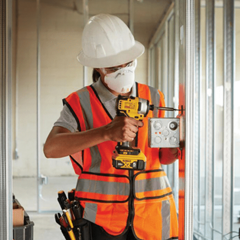 Person in construction gear, holding a power drill