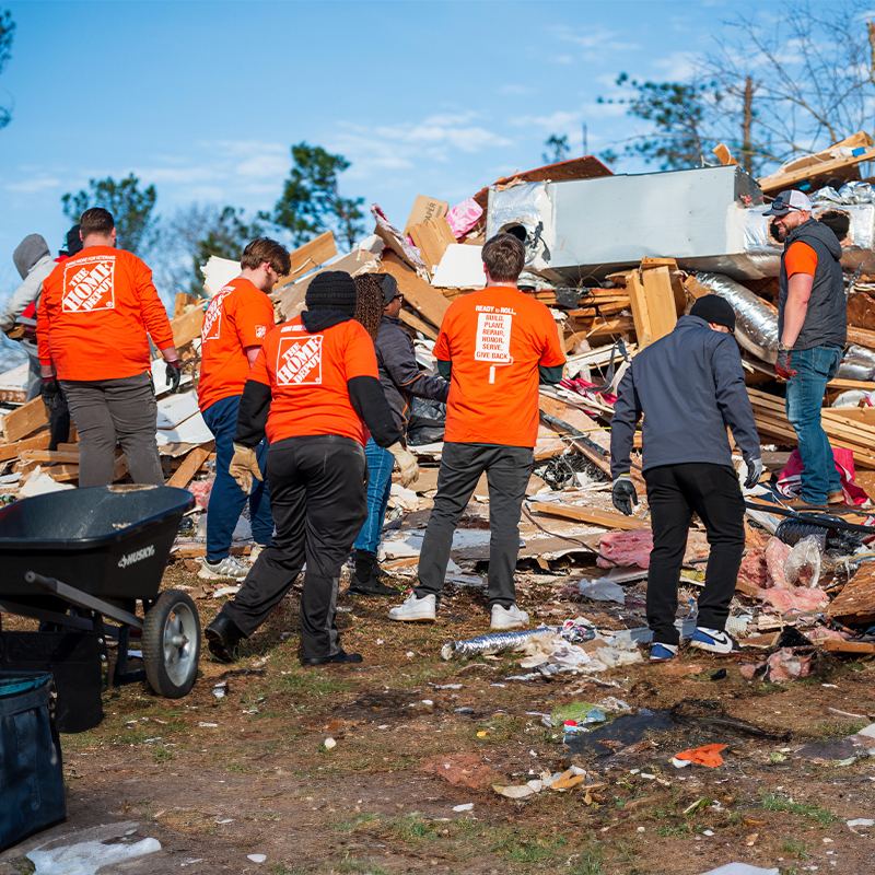 Volunteers standing in front of tornado damage