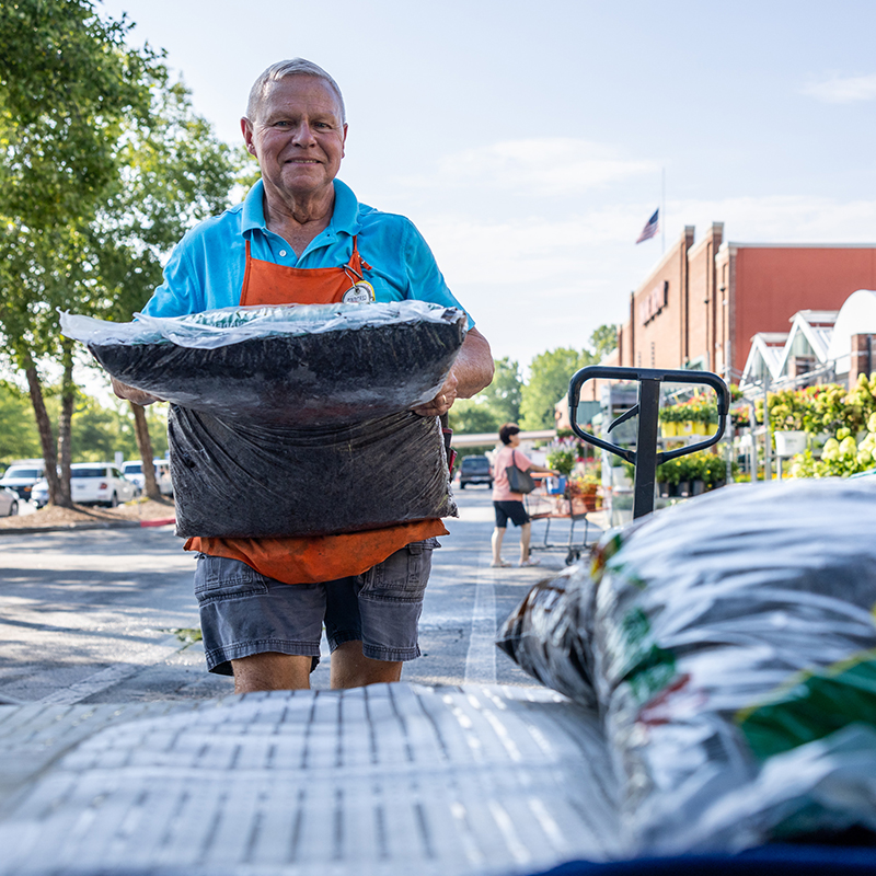 A Home Depot associate standing outside of the garden center with a bag of mulch