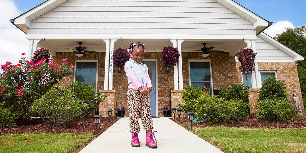 Young girl poses outside new Habitat for Humanity home