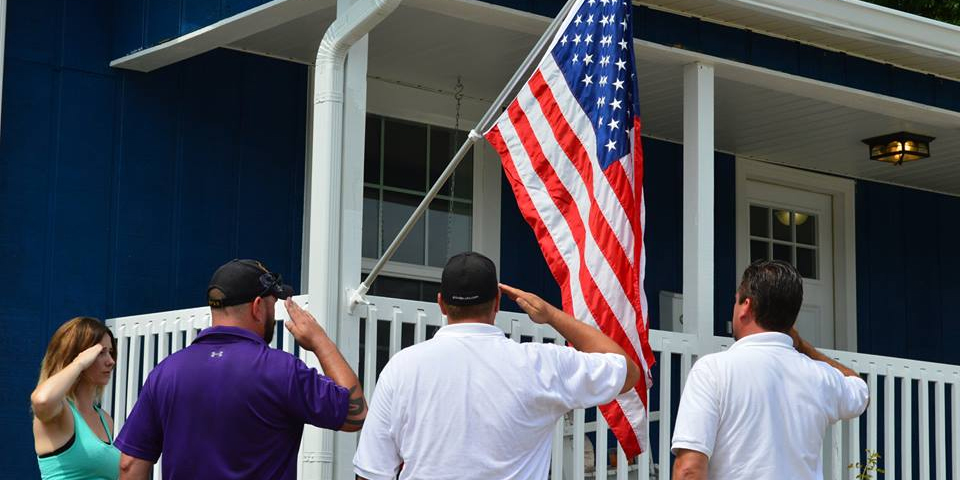 Purple Heart Homes volunteers saluting American flag