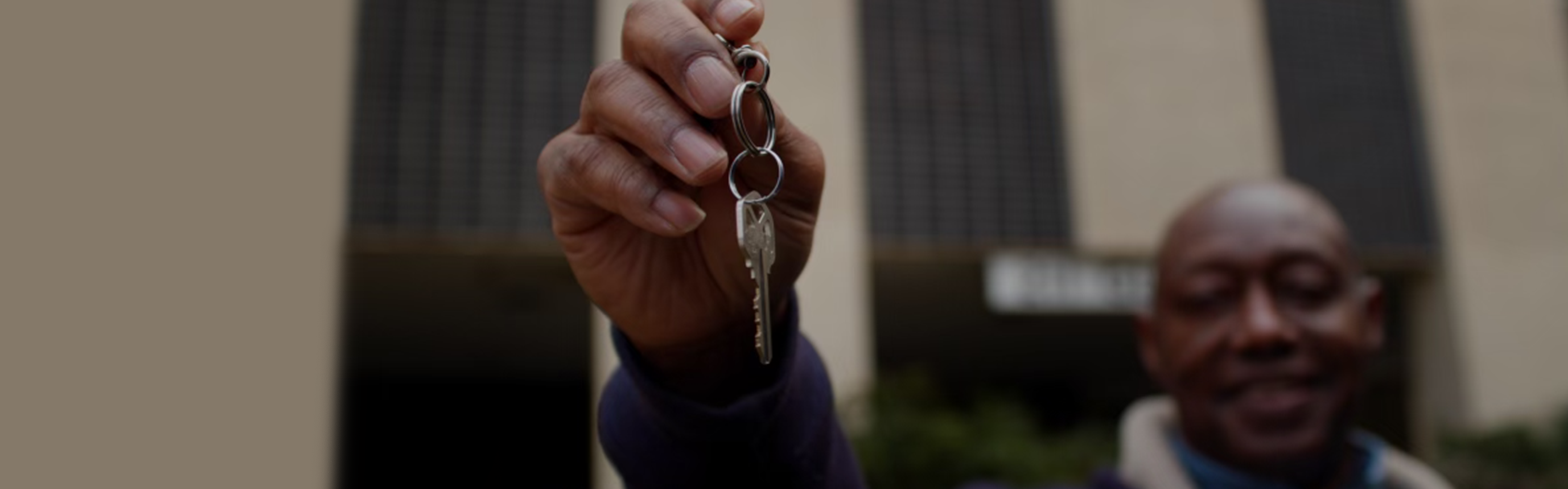 Man standing in front of building while holding keys