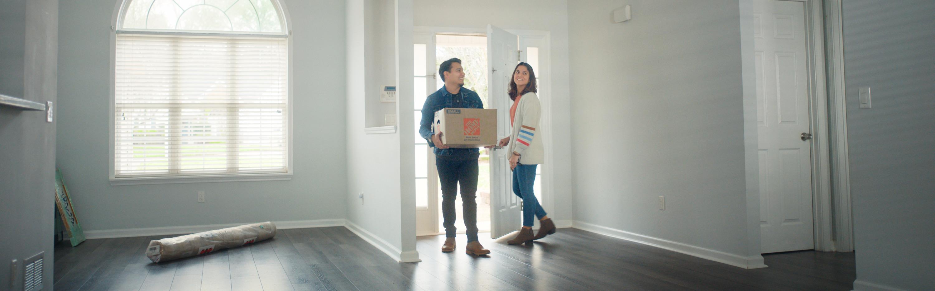 Couple carrying box into empty house