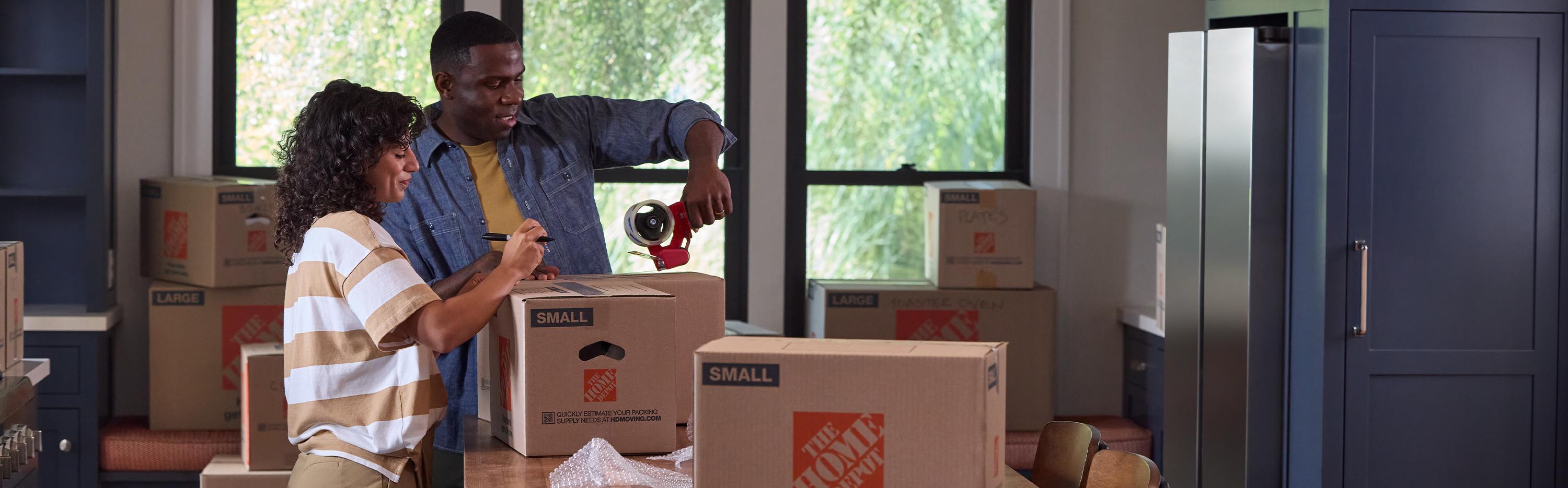 Two people packing Home Depot boxes