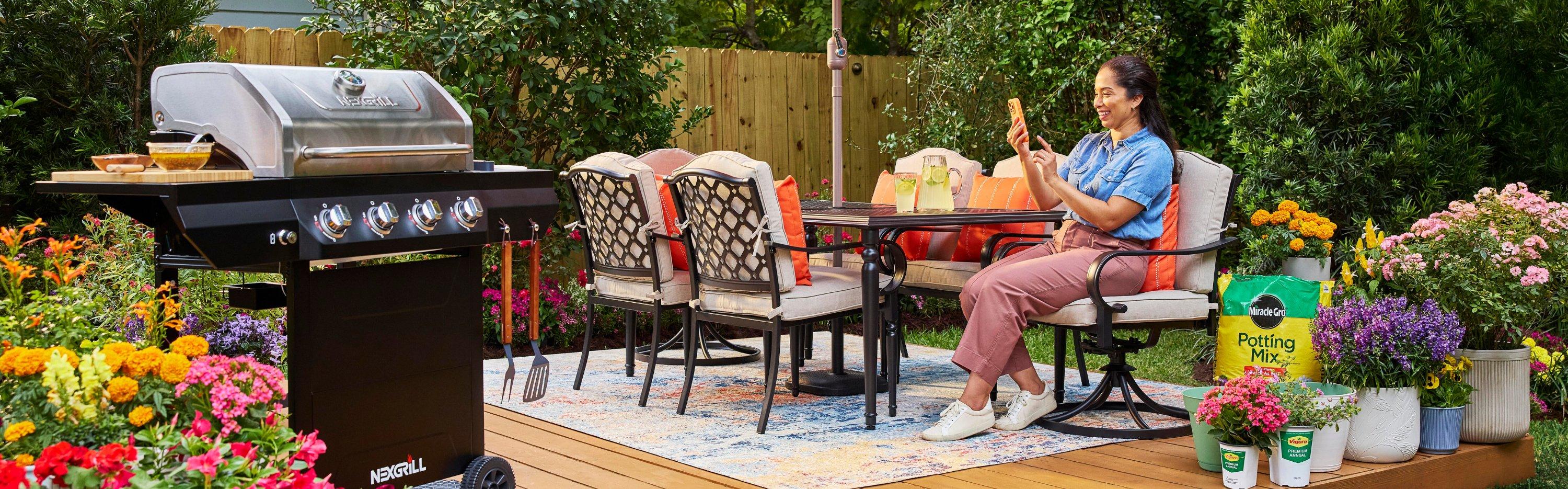 Customer on the phone on her deck with flowers and a grill