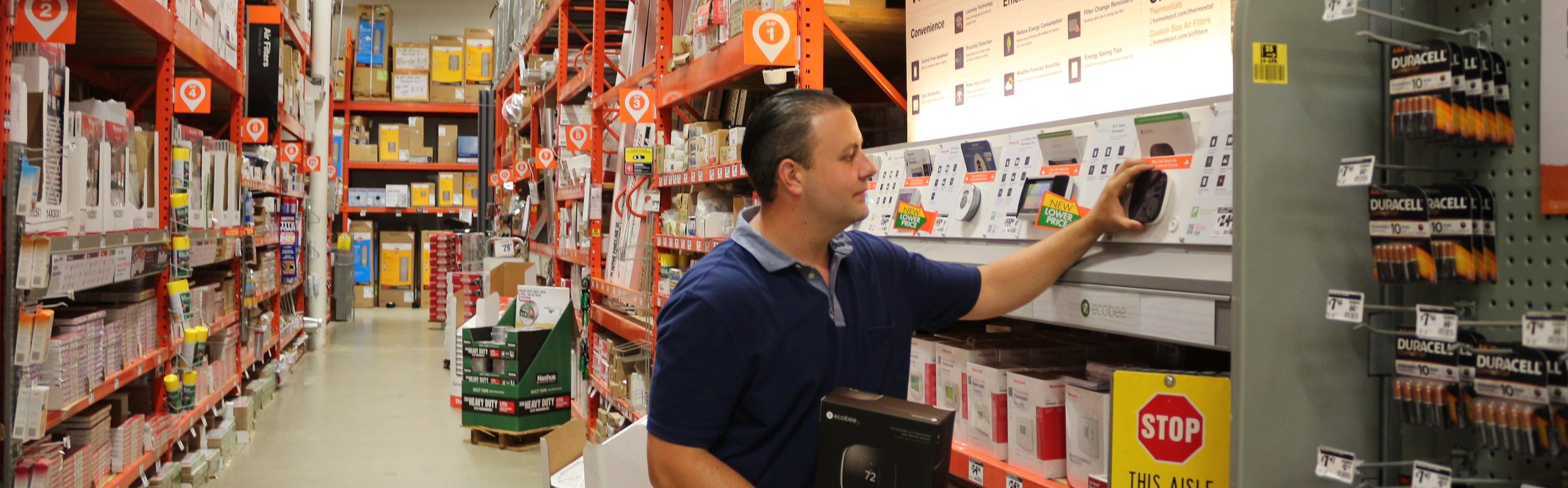 Home Depot associate looks at smart thermostats in-ailse