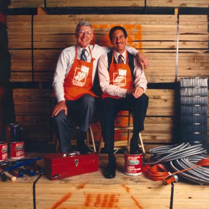 Bernie and Arthur sitting in front of lumber stack