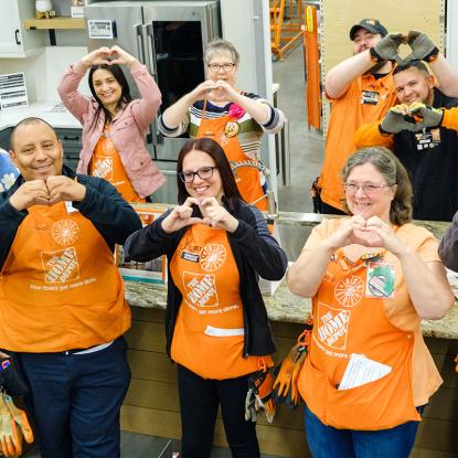 Home Depot associates posing making heart shapes with their hands