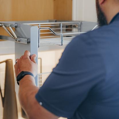 Maverick maneuvering a cabinet shelf in his kitchen