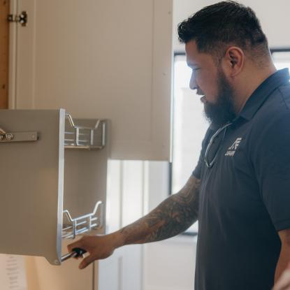 Maverick maneuvering a cabinet shelf in his kitchen