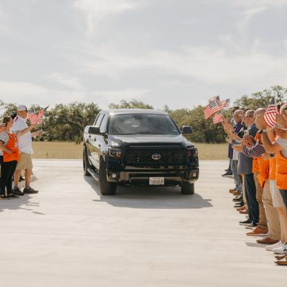 A truck pulling into a driveway with supporters on each side