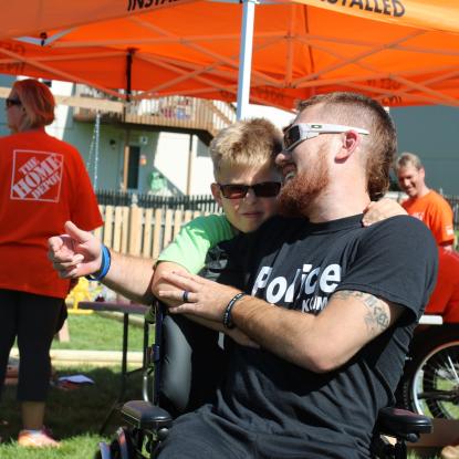 Veteran and son embrace as Team Depot volunteers work on yard makeover