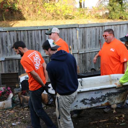 Volunteers move old bathtub through yard