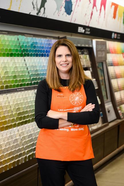 Woman in orange apron standing in front of paint samples