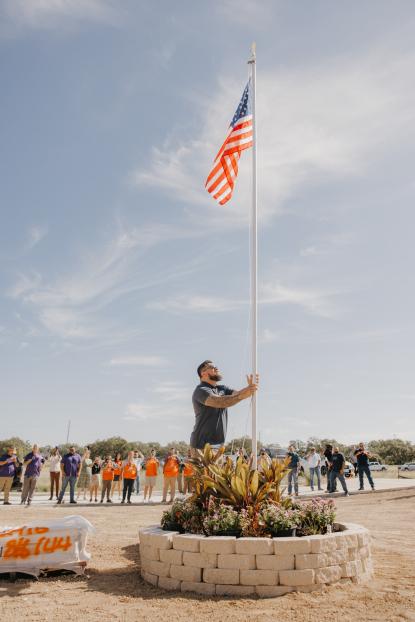 Sgt. Tu’ufuli raising the American flag outside his new home