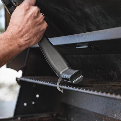 a hand using a grill brush to clean grill grates
