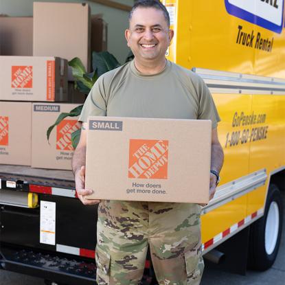 A service member holding a Home Depot moving box