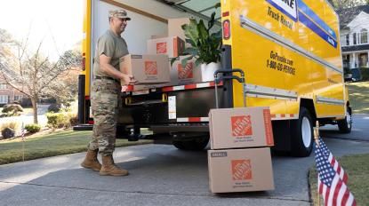 A service member moving a Home Depot moving box from a moving truck