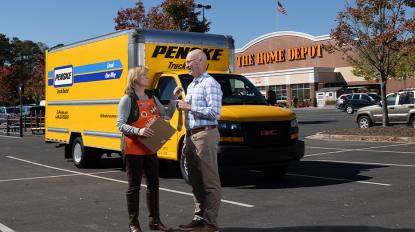 Two people in front of a moving truck outside a Home Depot store