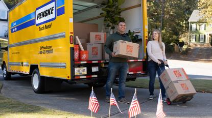Two people moving Home Depot moving boxes from a moving truck