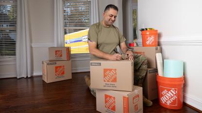 A service member writing on a Home Depot moving box