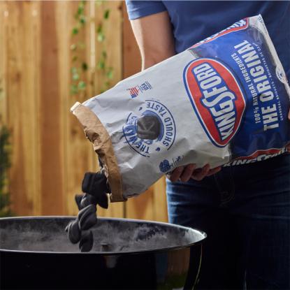 A man pouring charcoal into a grill